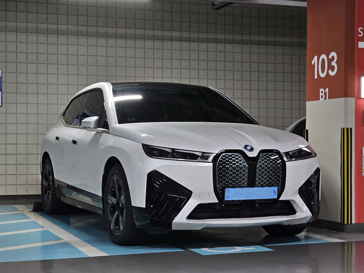 Front three-quarter view of a white 2022 BMW iX xDrive50 in a parking garage